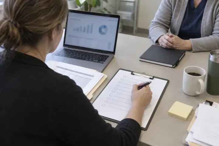 Medical practice managers reviewing an unlabeled checklist and billing dashboard at a plain table